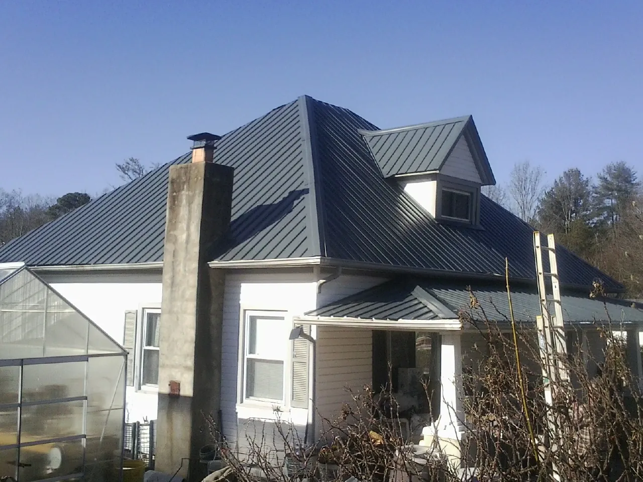 Dark blue standing seam metal roof on a white farmhouse with dormer — Slate & Tile Roof Repair by Roofing Brothers in Cumberland Center