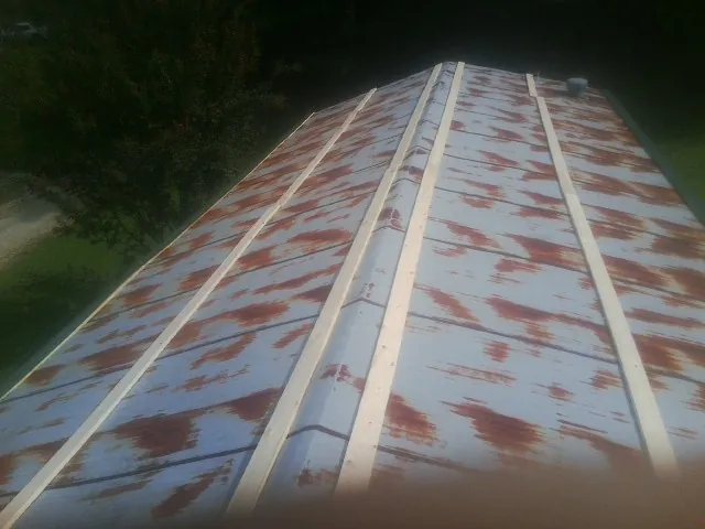 Rusted metal roof panels with new wood purlins before replacement — Storm Damage Roof Repair in Cumberland Center by Roofing Brothers