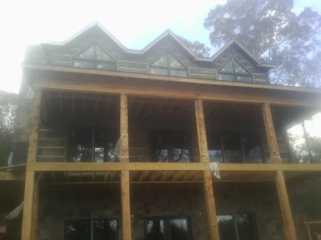 Dormers and porch framing on a large log home under construction — Roof Coating work by our crew in Cumberland Center