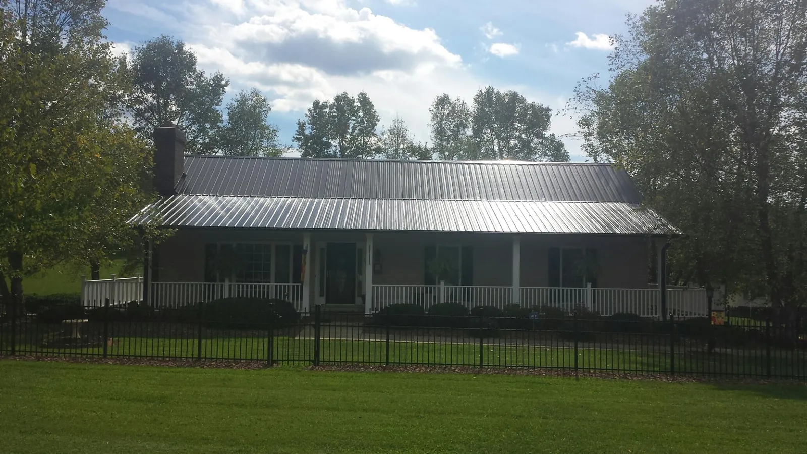 Gray metal roof on a brick ranch with a full width front porch — Gutter Guard Installation work by our crew in Cumberland Center