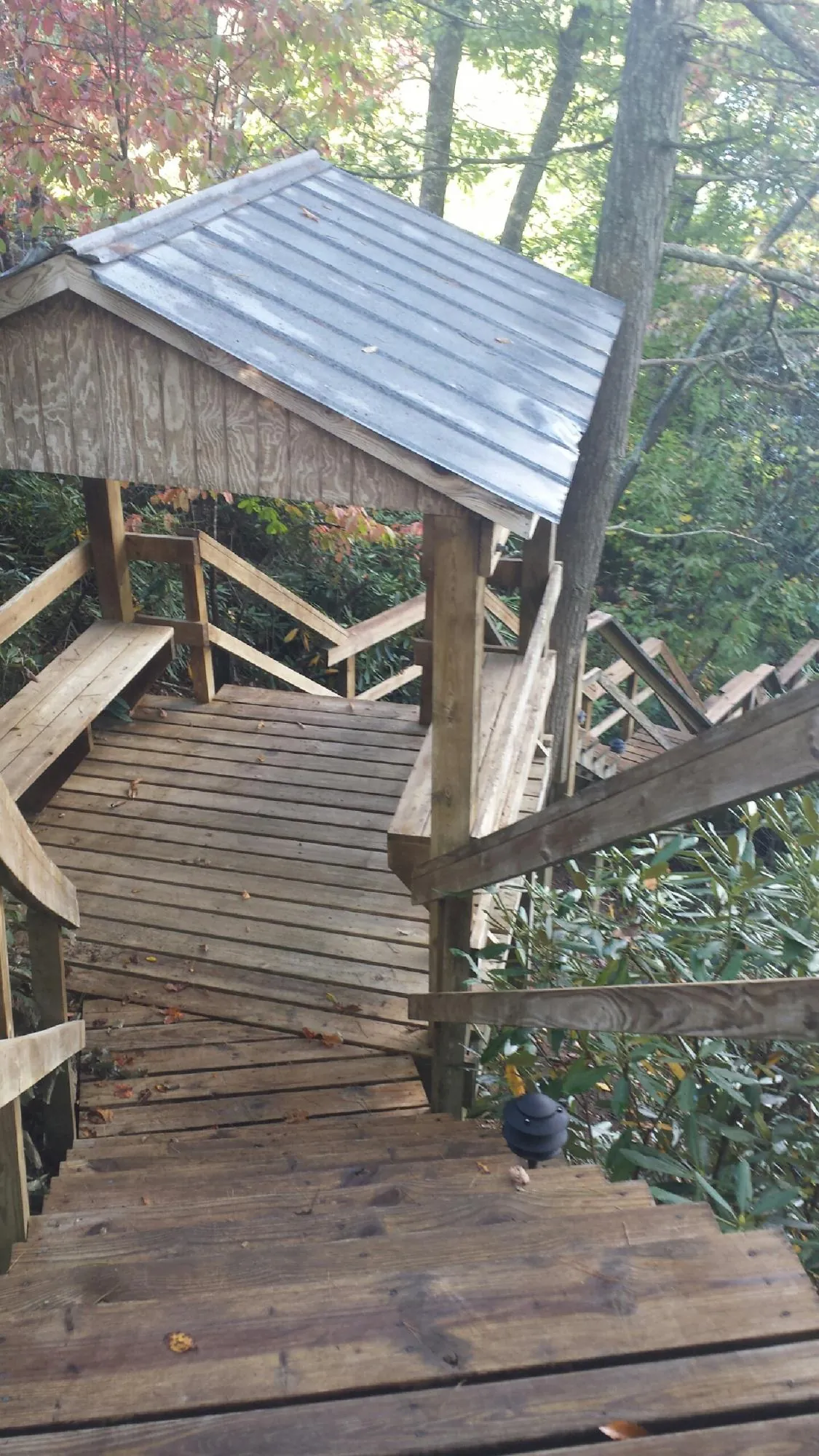 Metal roofed shelter over wooden steps on a wooded walkway — Skylight Repair & Installation work by our crew in Cumberland Center