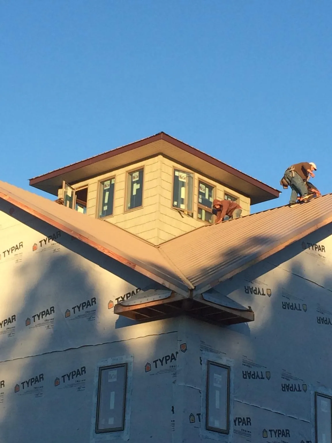 Roofers working around a rooftop cupola on a new metal roof at sunset — Roof Waterproofing in Cumberland Center by Roofing Brothers